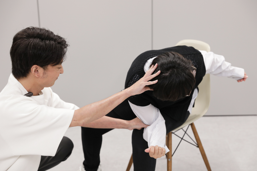 ひねりのストレッチを教えてもらう30代女性スタッフ