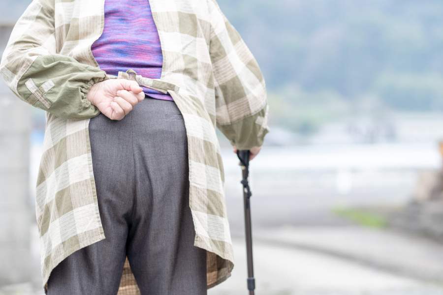 手を組んで歩いている老人