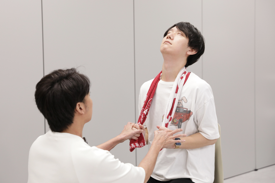 首のストレッチを教えてもらう20代男性スタッフ